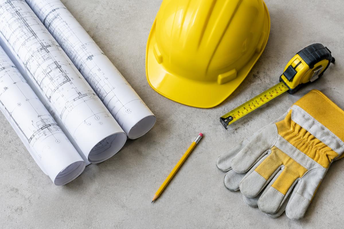 Blueprints, hard hat, tape measure and gloves